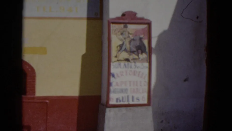 Yellow and red painted building wall with a printed bullfighting event poster bearing a matador illustration and Spanish text, Mexico, circa 1952.