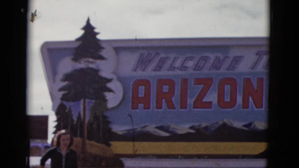 A closer 8mm view centers the Welcome to Arizona lettering and painted tree, with the posing woman cropped near the bottom left.