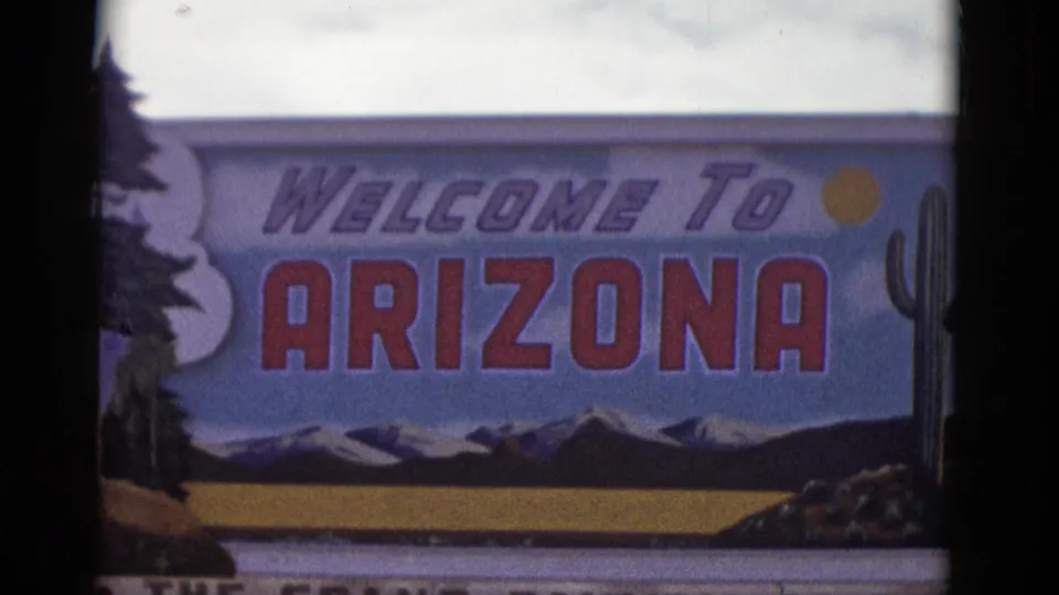 The final frame shows the Welcome to Arizona sign in close view, including painted mountains, a sun symbol, and a cactus at the edge.