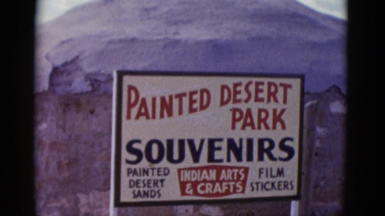 Painted Desert Park souvenir sign in front of rocky desert terrain.