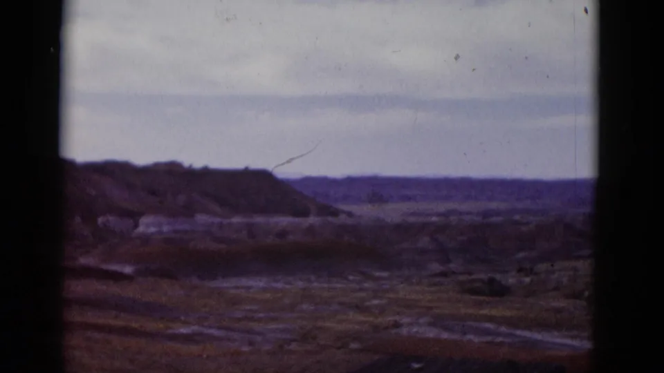 Wide 1952 Arizona desert view with low ridges, open terrain, and a distant horizon beneath an overcast sky.
