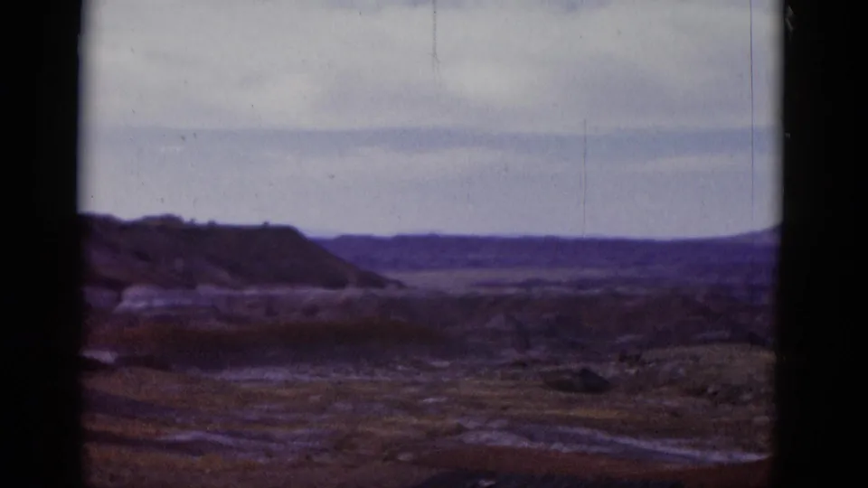 1952 Arizona home-movie frame showing a broad Painted Desert landscape with ridges, open plain, and soft cloudy light.