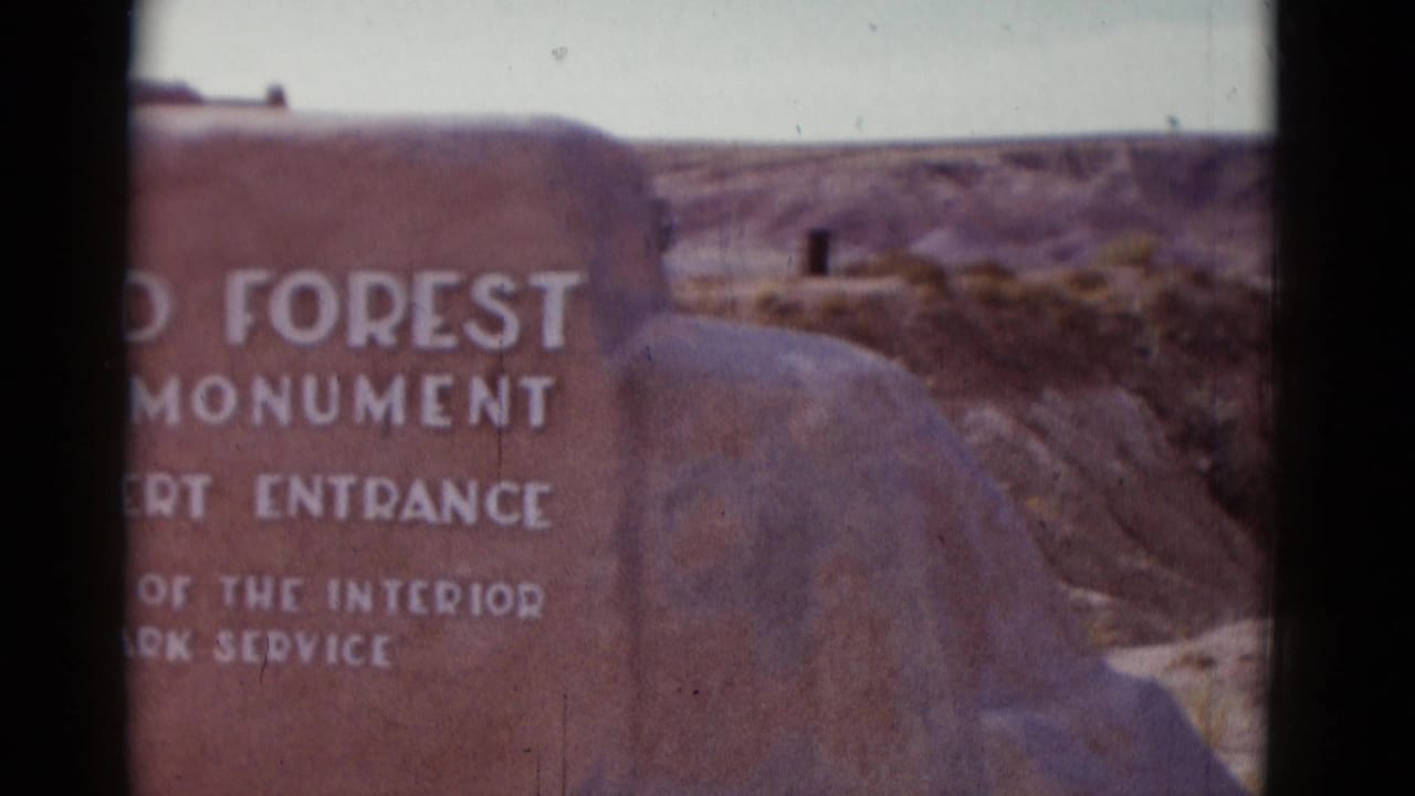 Partial stone monument entrance marker beside a desert canyon landscape.