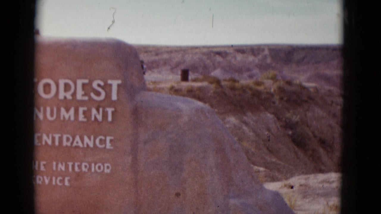 Stone marker reading in part “FOREST MONUMENT” with canyon ridges beyond.