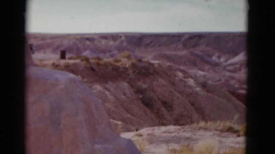 1952 Arizona home-movie view of reddish dry desert hills, cracked slopes, sparse vegetation, and a pale sky.