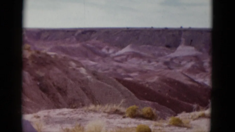 Final frame of the Arizona desert landscape shows eroded reddish slopes, small shrubs, and dark 8mm border areas.