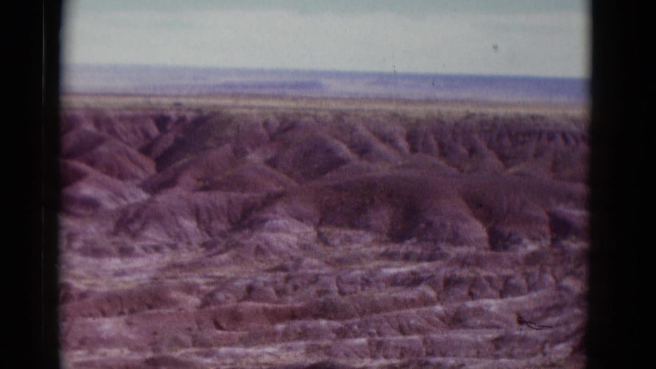 Eroded desert hills and a pale horizon seen through dark 8mm film borders.