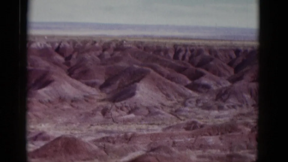 1952 Arizona 8mm frame showing rolling reddish desert hills, gullies, and a pale distant horizon.