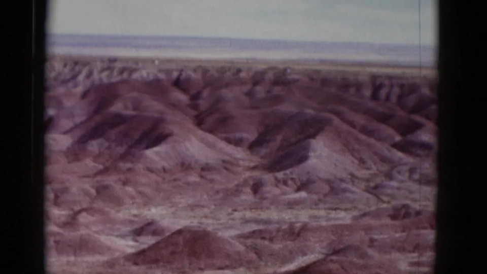 1952 Arizona 8mm frame with layered desert ridges, rounded reddish hills, and a distant flat horizon.
