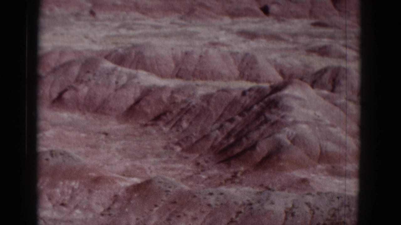 1952 8mm travel footage view of layered desert canyon terrain in Arizona, framed by dark film edges and faded color.