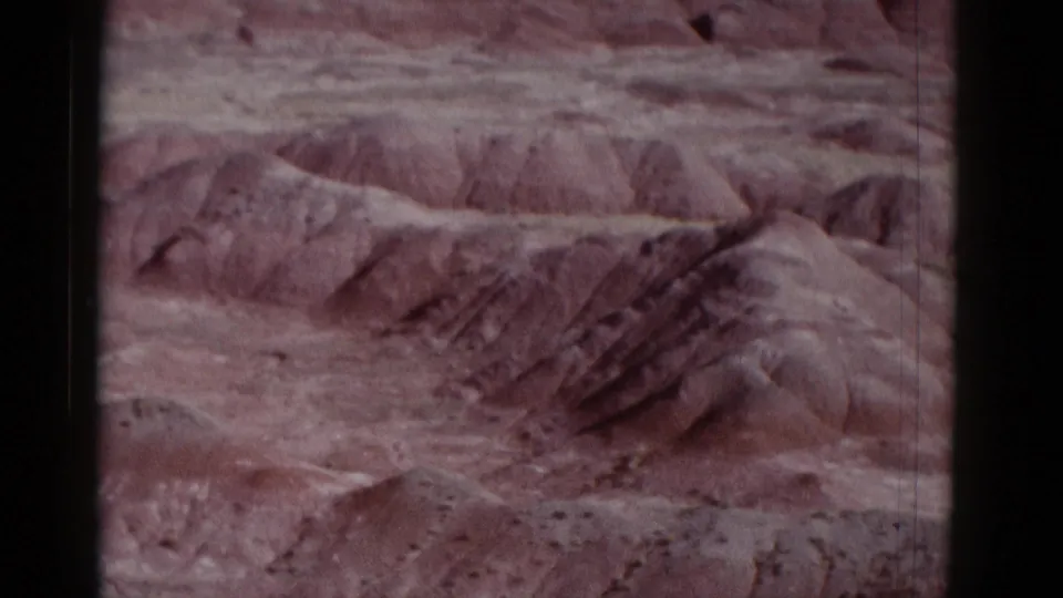 1952 8mm travel footage view of layered desert canyon terrain in Arizona, framed by dark film edges and faded color.