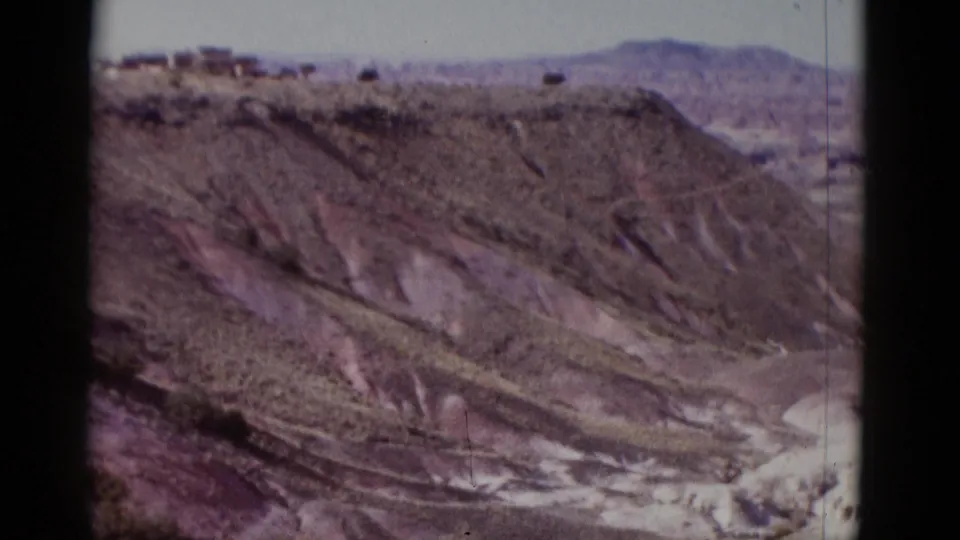 1952 Arizona 8mm frame showing a wide view of layered desert hills with a distant mountain line beyond.