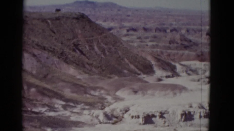 1952 Arizona home-movie view across layered desert rock formations and a broad, dry canyon basin.