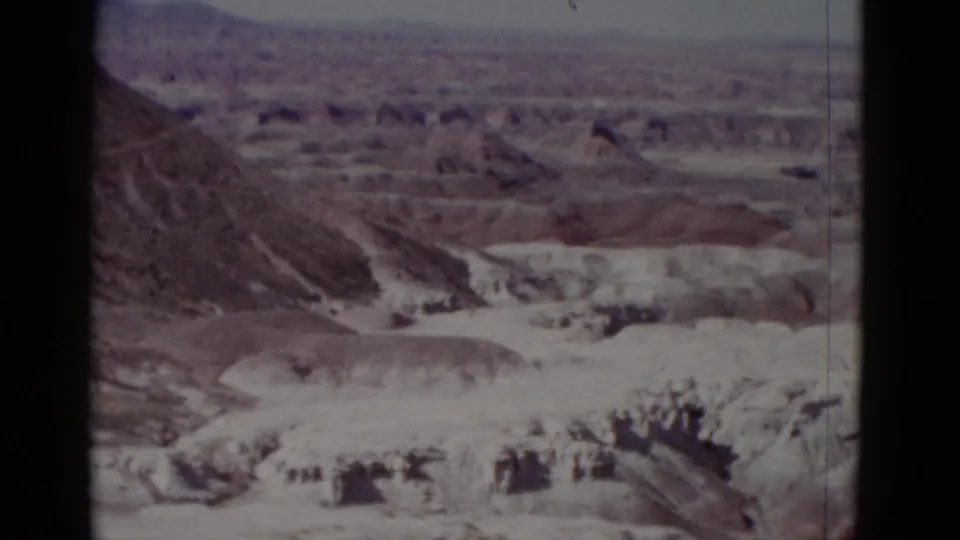 1952 Arizona home-movie frame ending on a wide canyon panorama with eroded ridges and pale desert formations.