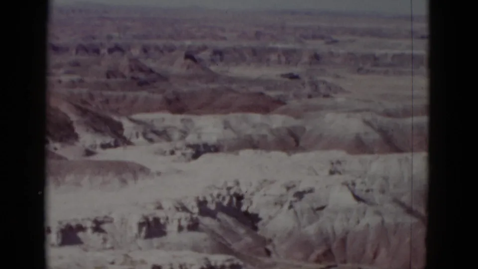1952 Arizona 8mm view of layered dry desert formations and eroded ridges, with no visible people, buildings, or signage.