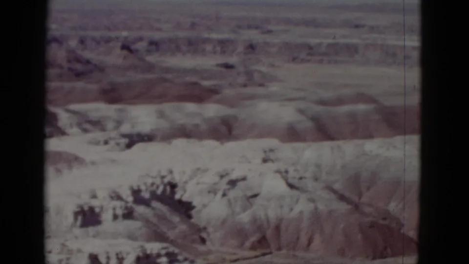 1952 Arizona 8mm frame with dry eroded canyon slopes, reddish ridges, and faded color typical of home-movie footage.