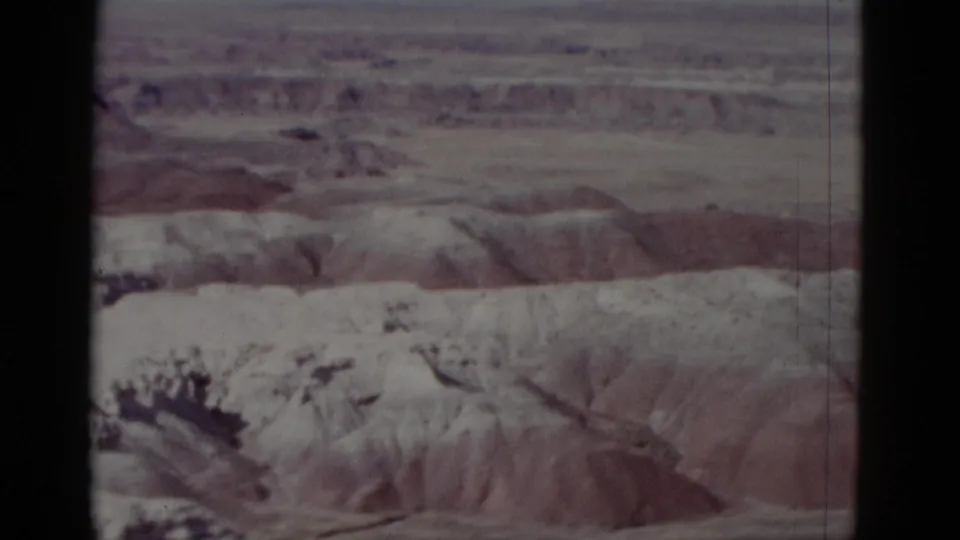 1952 Arizona 8mm view of dry canyon wall, muted brown ridges, and open desert horizon, with no human figures visible.
