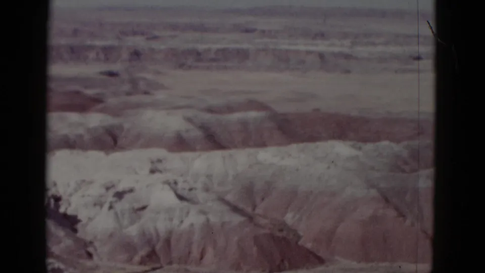 Faded 1952 8mm view of an arid Arizona landscape with pale ridges and dark vertical film-frame borders.