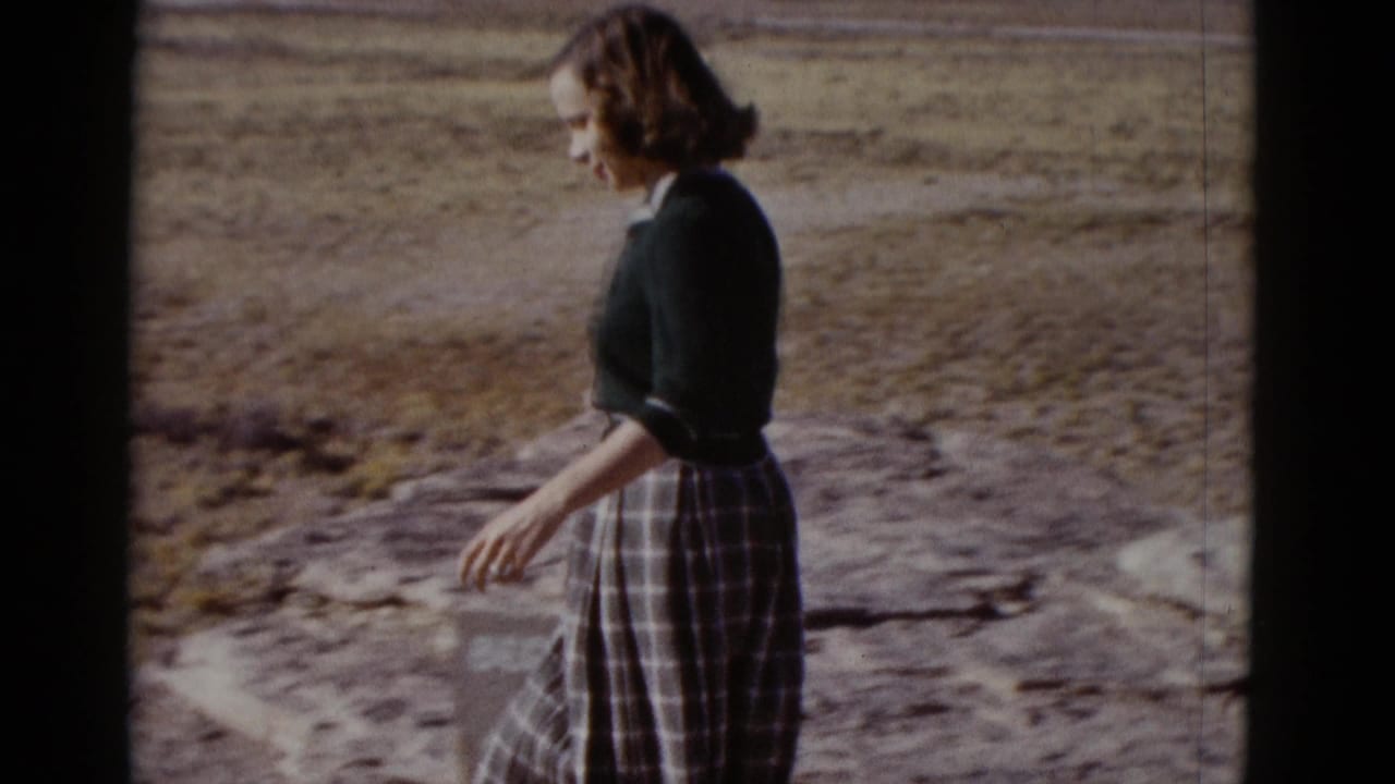 Profile view of a woman walking over sunlit rocky desert ground, supported by metadata as Arizona, 1952.