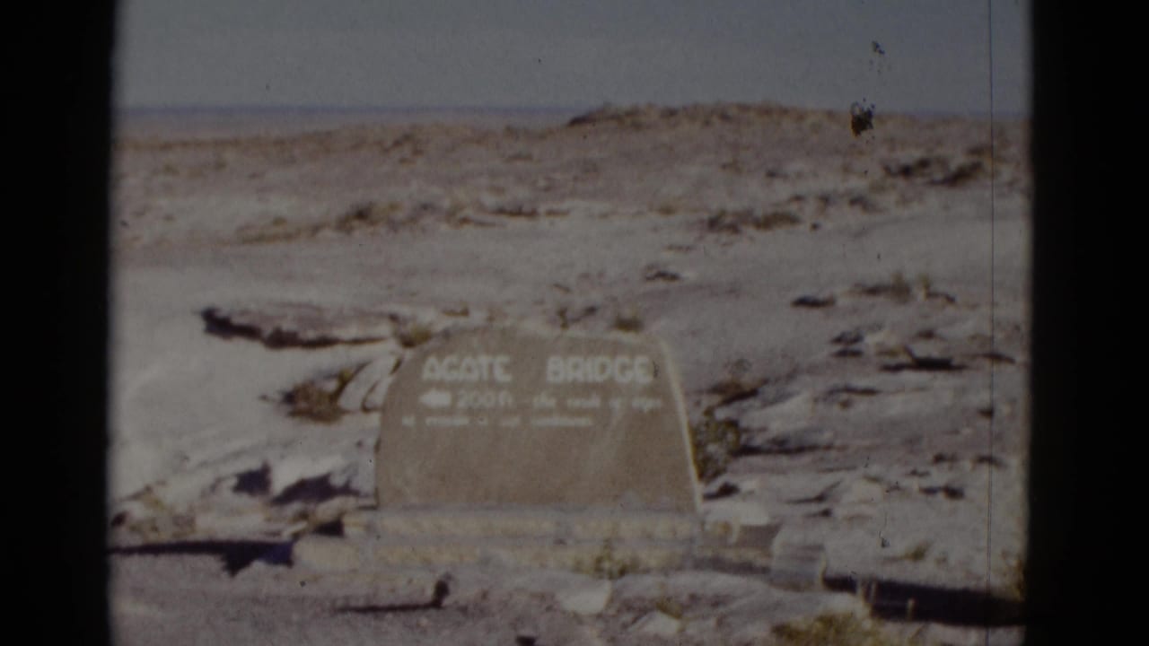 Weathered Agate Bridge sign set in rocky desert terrain.