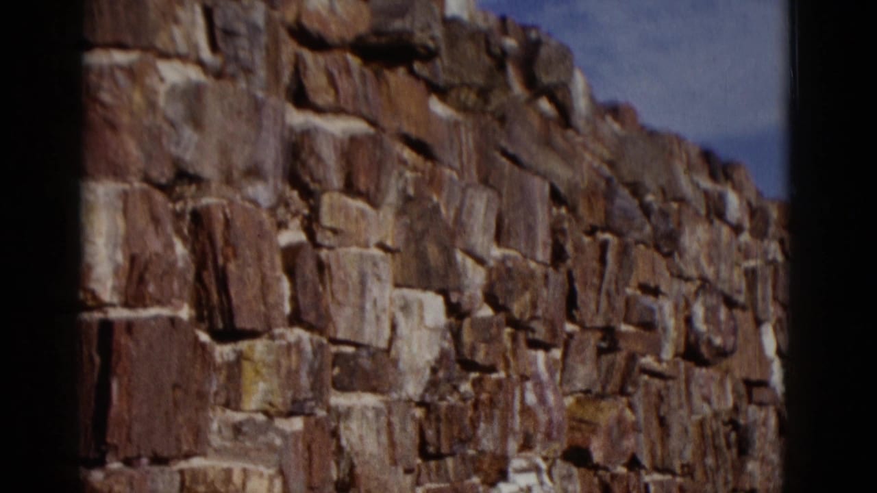 Close view of a rough red-brown stone wall with blue sky above.