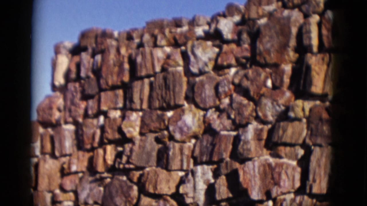 Close view of a rough stone wall against a clear blue sky.