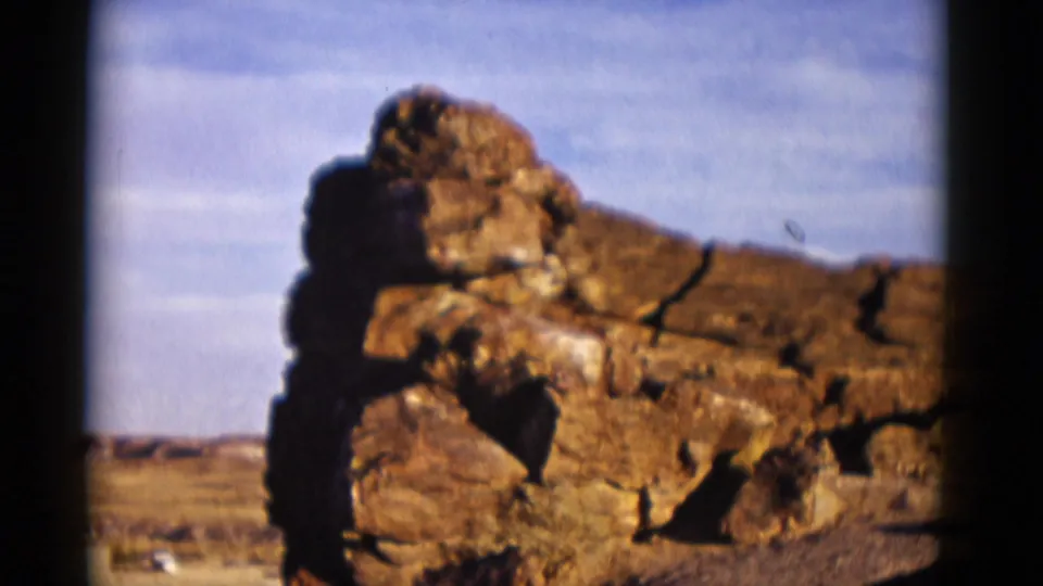 A brief cutaway shows stacked desert rocks in warm 8mm color, likely from the same Arizona travel sequence.