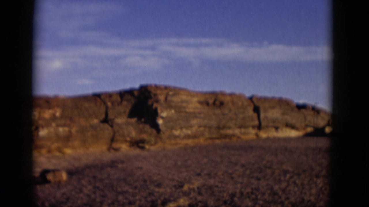 Low rock formation and barren ground framed by dark vertical edges.