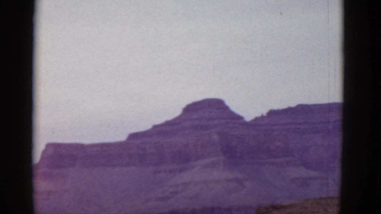Layered desert cliffs and a pale sky seen through dark film-frame borders.