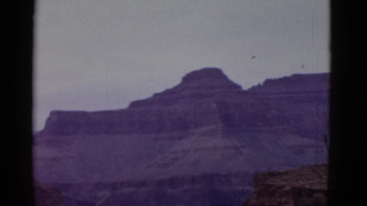 Distant canyon ridges with a darker foreground rock edge at the lower right.