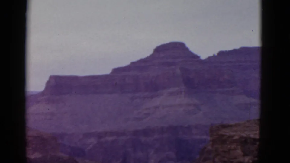 1952 Arizona travel footage frame with layered desert cliffs, soft focus, and the dark edges of the scanned 8mm frame.