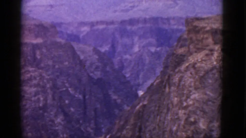 1952 8mm Grand Canyon view showing a deep ravine, layered canyon walls, and a rocky foreground ridge in Arizona.