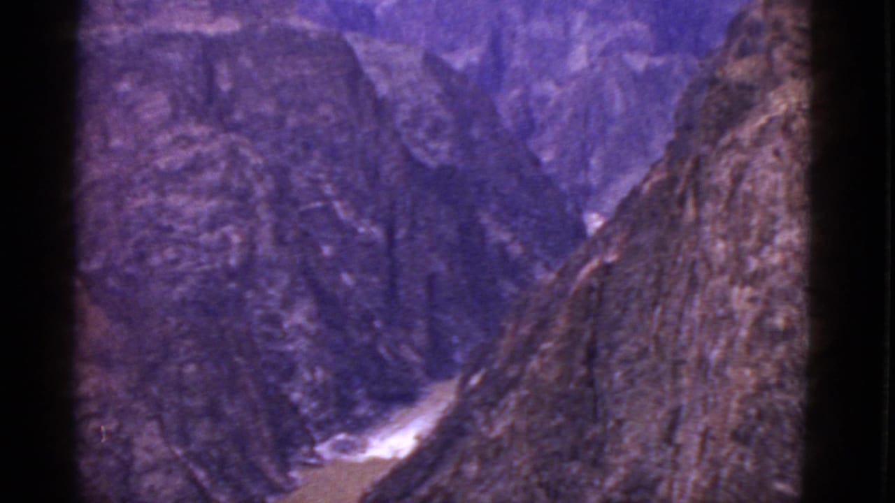 1952 Arizona 8mm frame showing a muddy creek running between steep, shadowed canyon walls with a purple film cast.