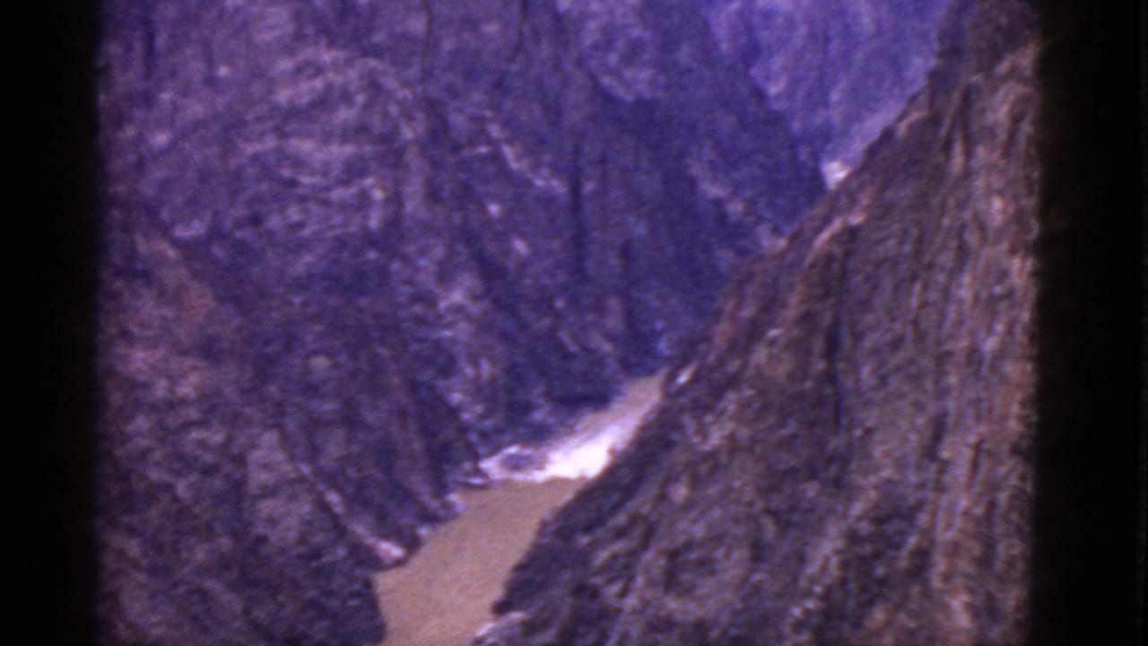 Rocky canyon with a muddy creek curving through the valley floor.