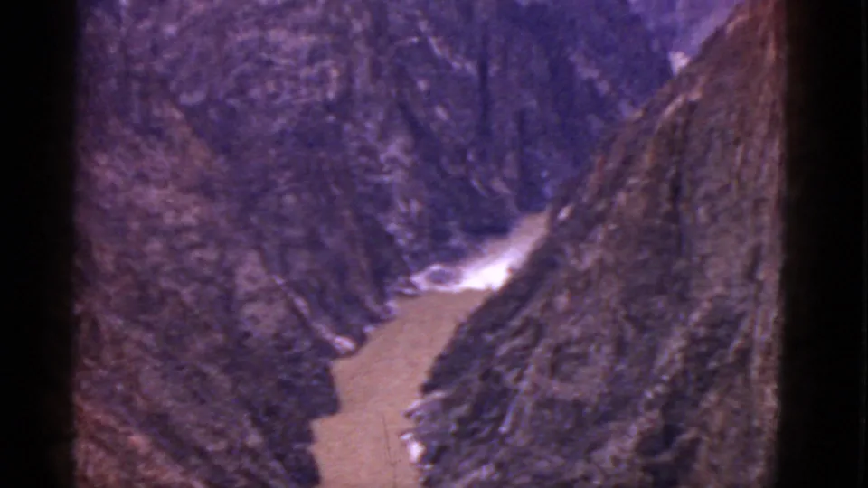 1952 Arizona 8mm frame with a muddy creek below steep rock walls, softened by grain and a noticeable purple color shift.