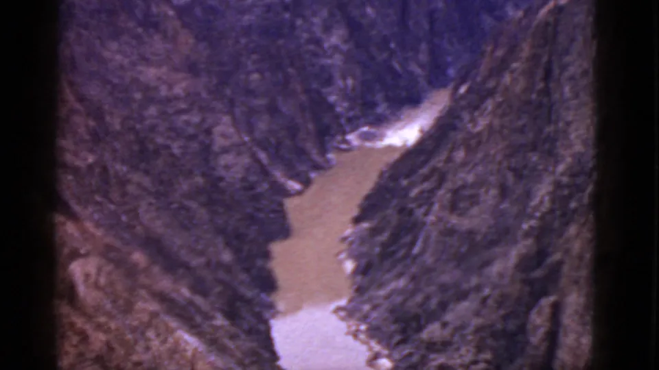 1952 Arizona 8mm frame showing a close view down the canyon where brown water and whitewater pass between rugged cliffs.