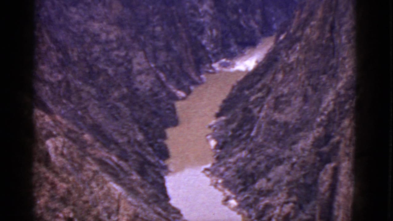 1952 Arizona 8mm frame showing a muddy river cutting through rugged canyon-like terrain under bright daylight.