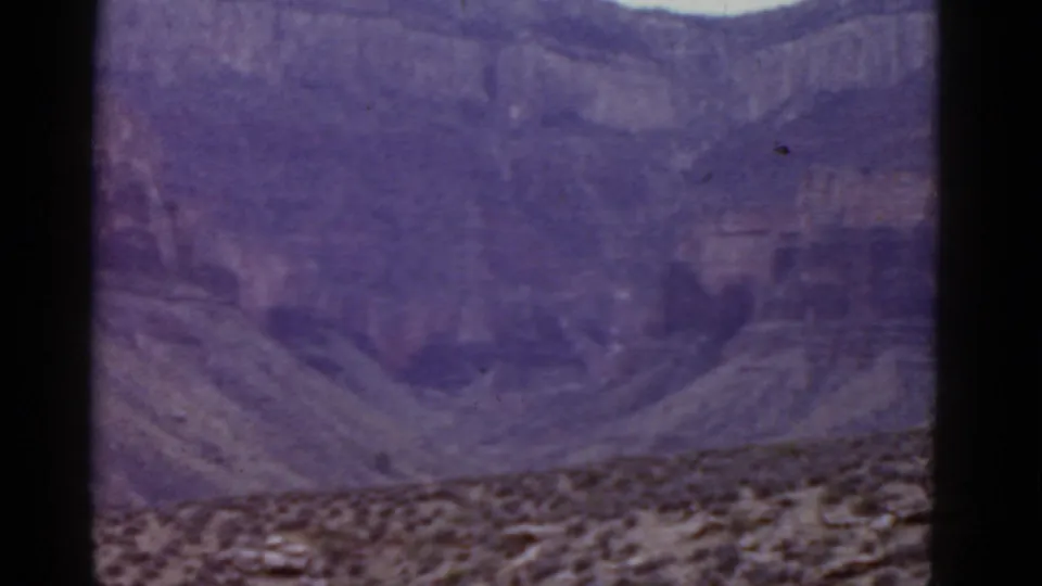 Arizona desert terrain in a 1952 8mm frame, with cliff bands, scrubby foreground, and soft faded color.