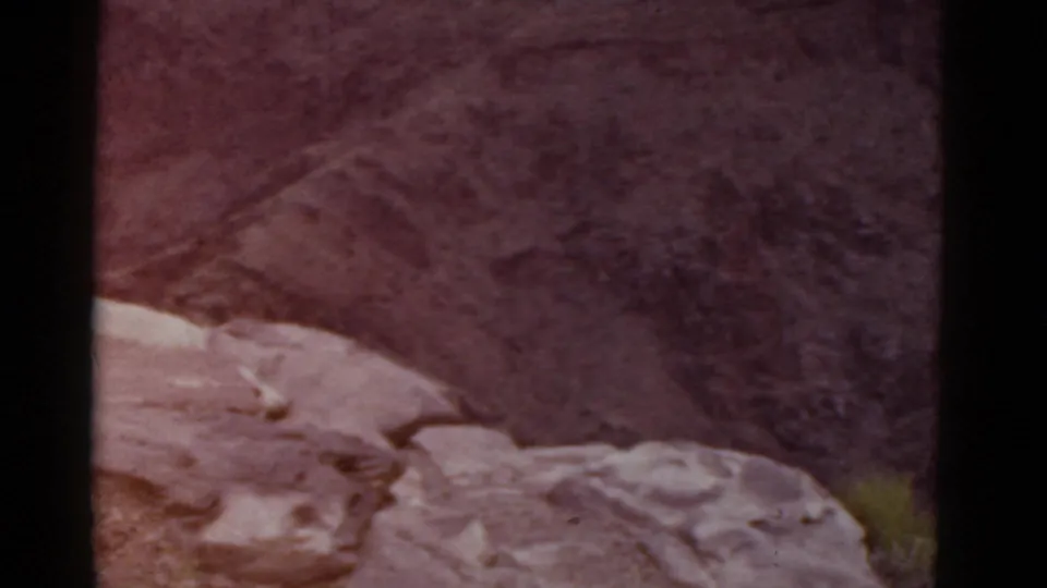 End frame of the 1952 Arizona pan, showing a rocky ledge before darker desert slopes under a reddish aged-film cast.