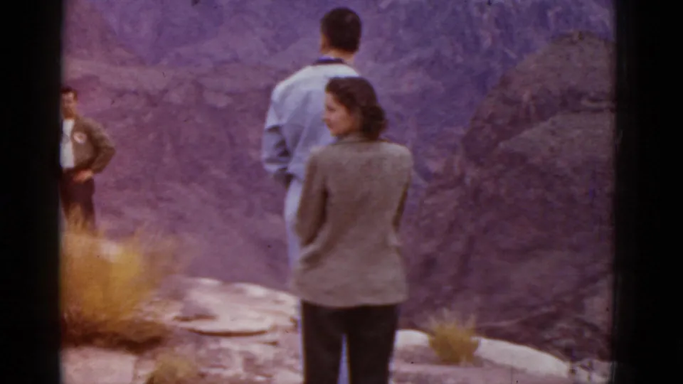 1952 Arizona 8mm frame of adults at a canyon overlook, including a woman in a jacket and men facing the view.