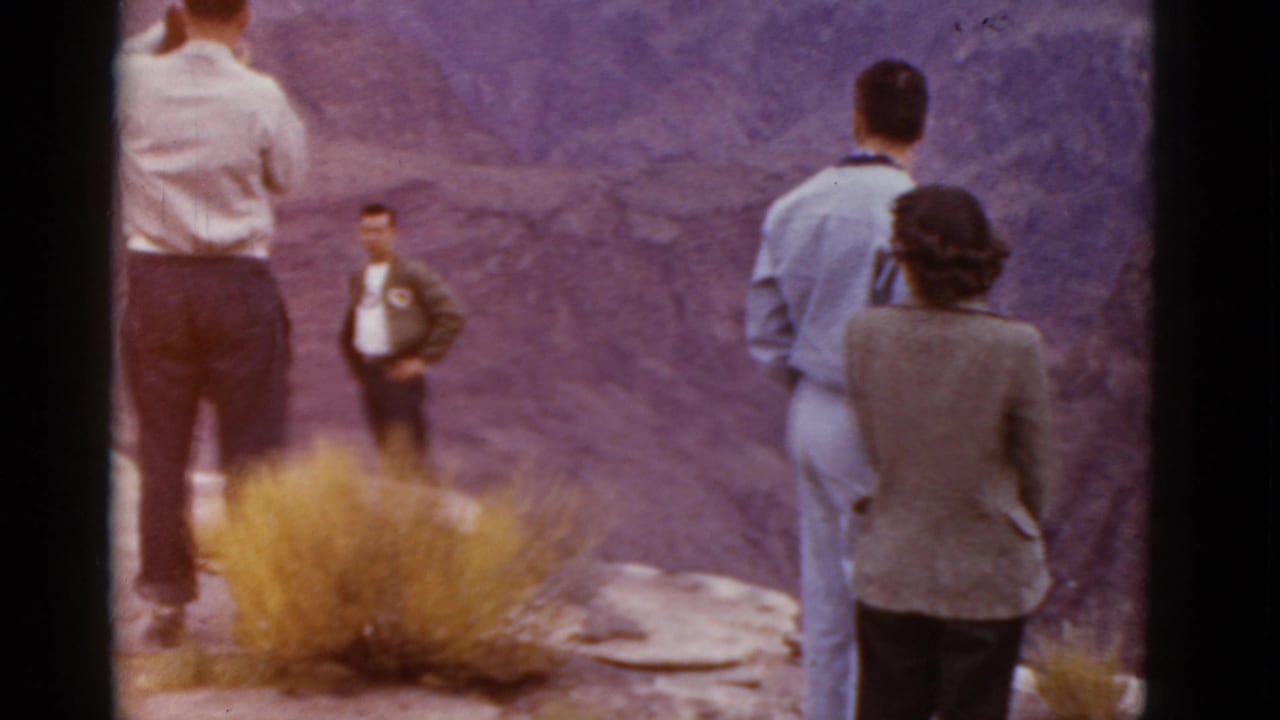 Adults at an Arizona canyon overlook in 1952, with a man in a light shirt near a shrub and others looking outward.