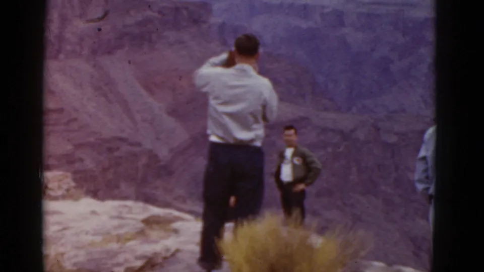 At an Arizona overlook in 1952, a man lifts a still camera while others remain near the canyon edge.