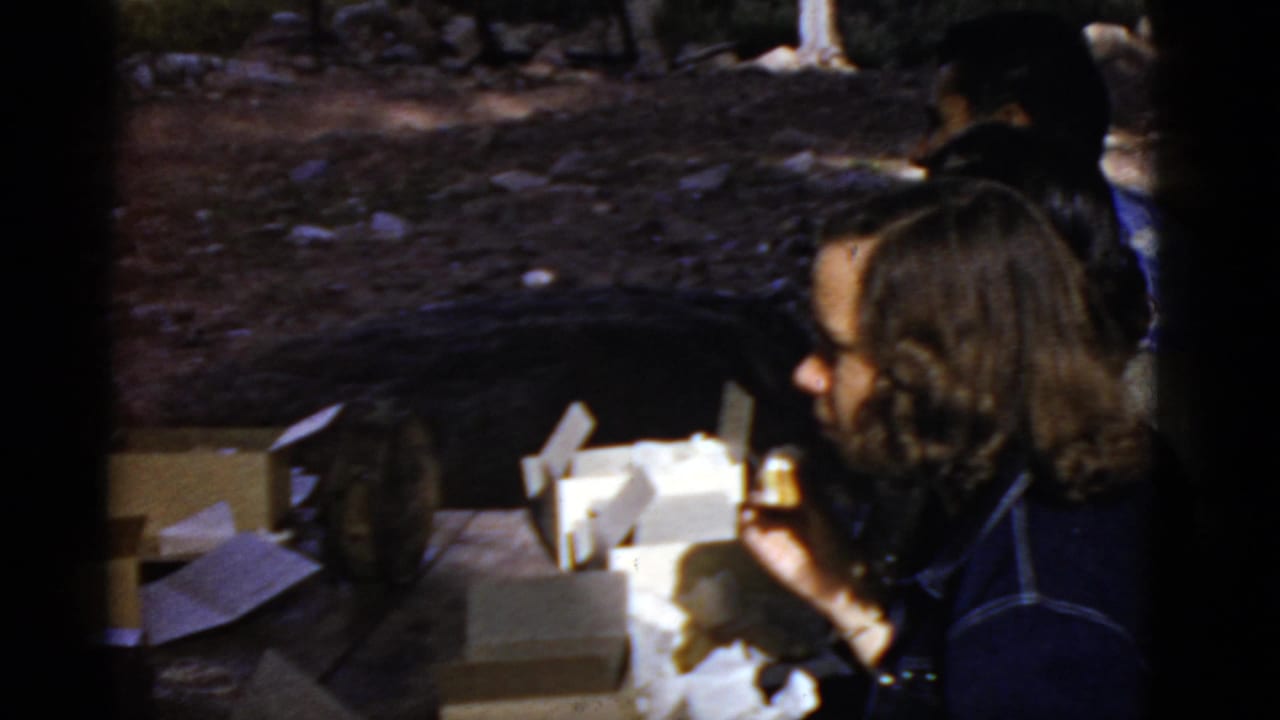 Women seated outdoors near open boxes during a picnic.