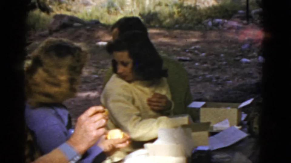 1952 Arizona vacation frame showing women gathered around picnic boxes, with one holding food in the foreground.
