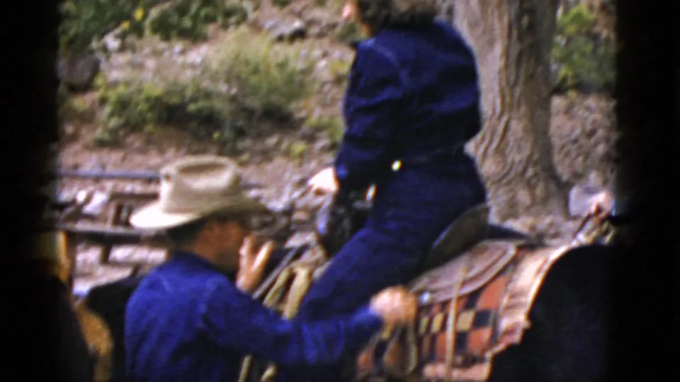 A woman sits astride the saddled horse while a man in a cowboy hat stands nearby in the 1952 Arizona home-movie scene.