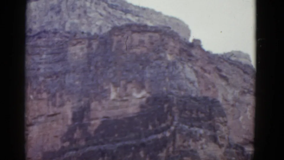 1952 Arizona home-movie frame showing the pan higher on the cliff, with layered rock filling most of the view.