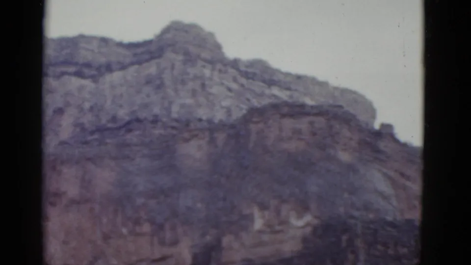 1952 Arizona 8mm frame ending on the higher cliff ridge, with pale sky above and softened archival color.