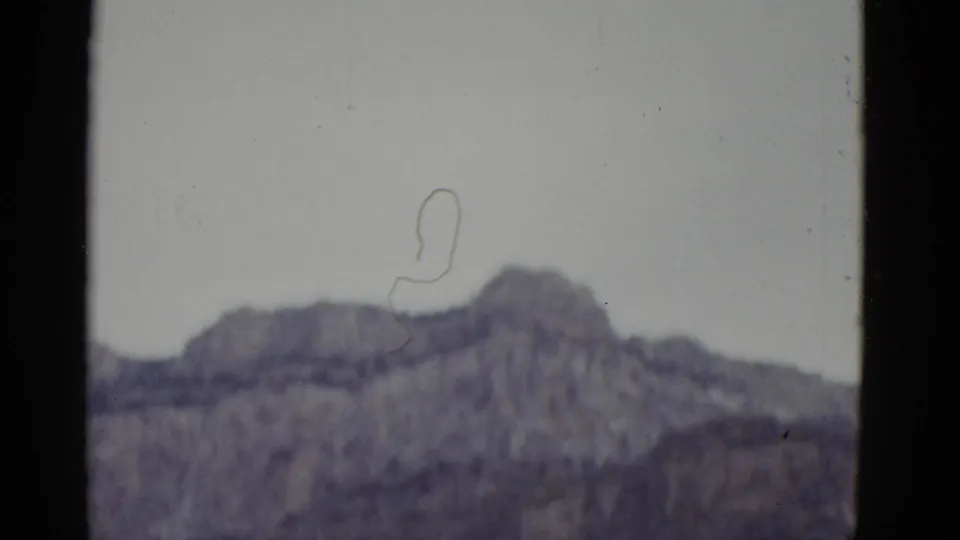 Soft, grainy 1952 Arizona 8mm view of a distant mountain ridge framed by dark film edges.
