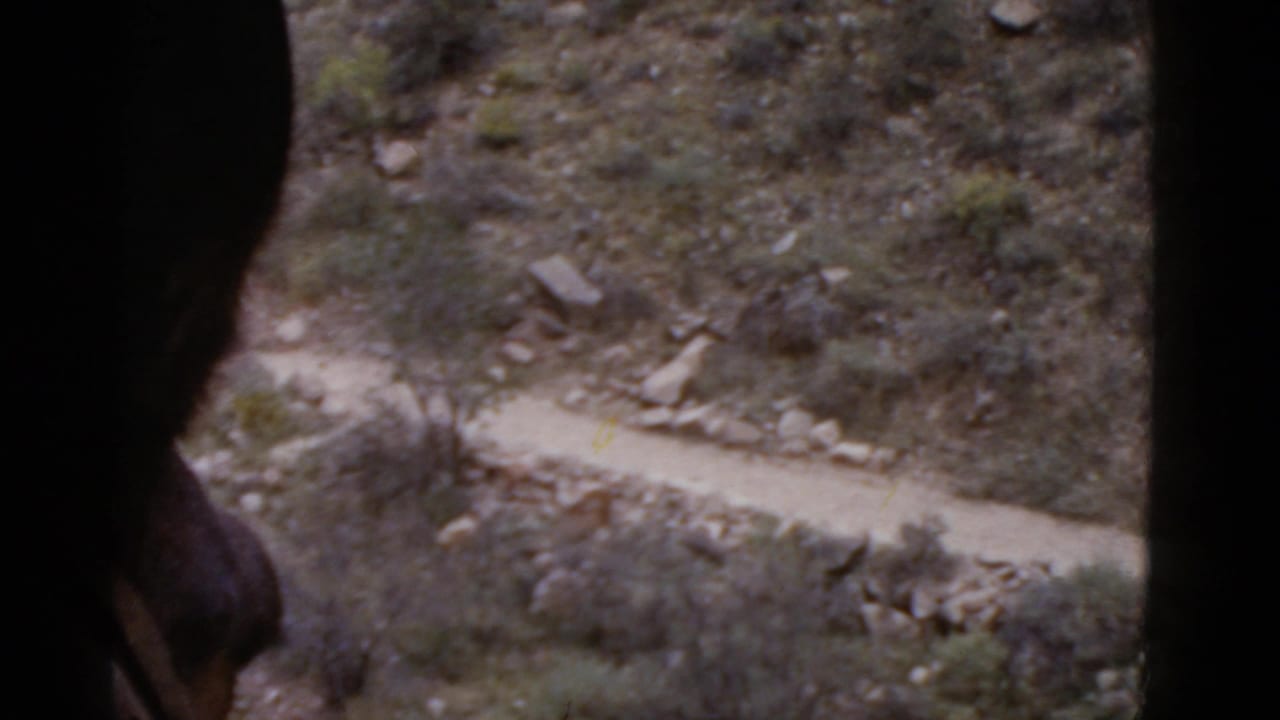 Dark foreground shape over a rocky slope and narrow desert trail below.
