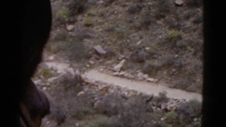 A dark foreground shape, likely part of the rider or mount, passes over the 1952 Arizona trail view.